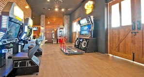 A gaming arcade with multiple arcade machines, a jukebox, and a jukebox with a screen.