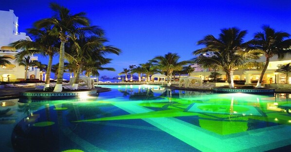 A swimming pool with palm trees and a building in the background.