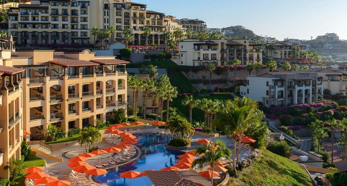 Un resort con piscina rodeada de palmeras y sillas de descanso.