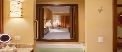A hotel bathroom with a vanity, a mirror, and a towel rack.