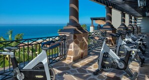 Outdoor exercise equipment, a stone floor, and a view of the ocean.