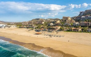 A coastal resort with beachfront villas, a sandy beach, and a clear sky.