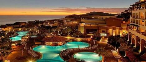 Un resort con varias piscinas, vista a la playa y una variedad de edificios.