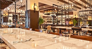 A restaurant with marble tables, metal chandeliers, and a warm ambiance.