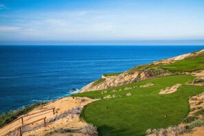 A coastal golf course with a clear view of the ocean.