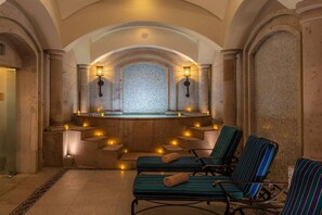 A spa area with stone walls, a central seating area with chairs, and wall-mounted lighting.