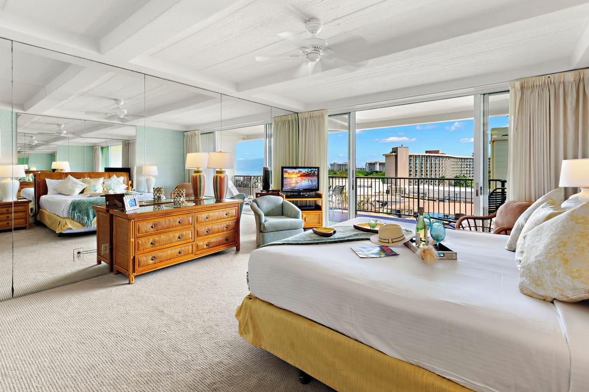 Une chambre d’hôtel avec un grand lit, une commode, une télévision et un balcon offrant une vue sur la ville.