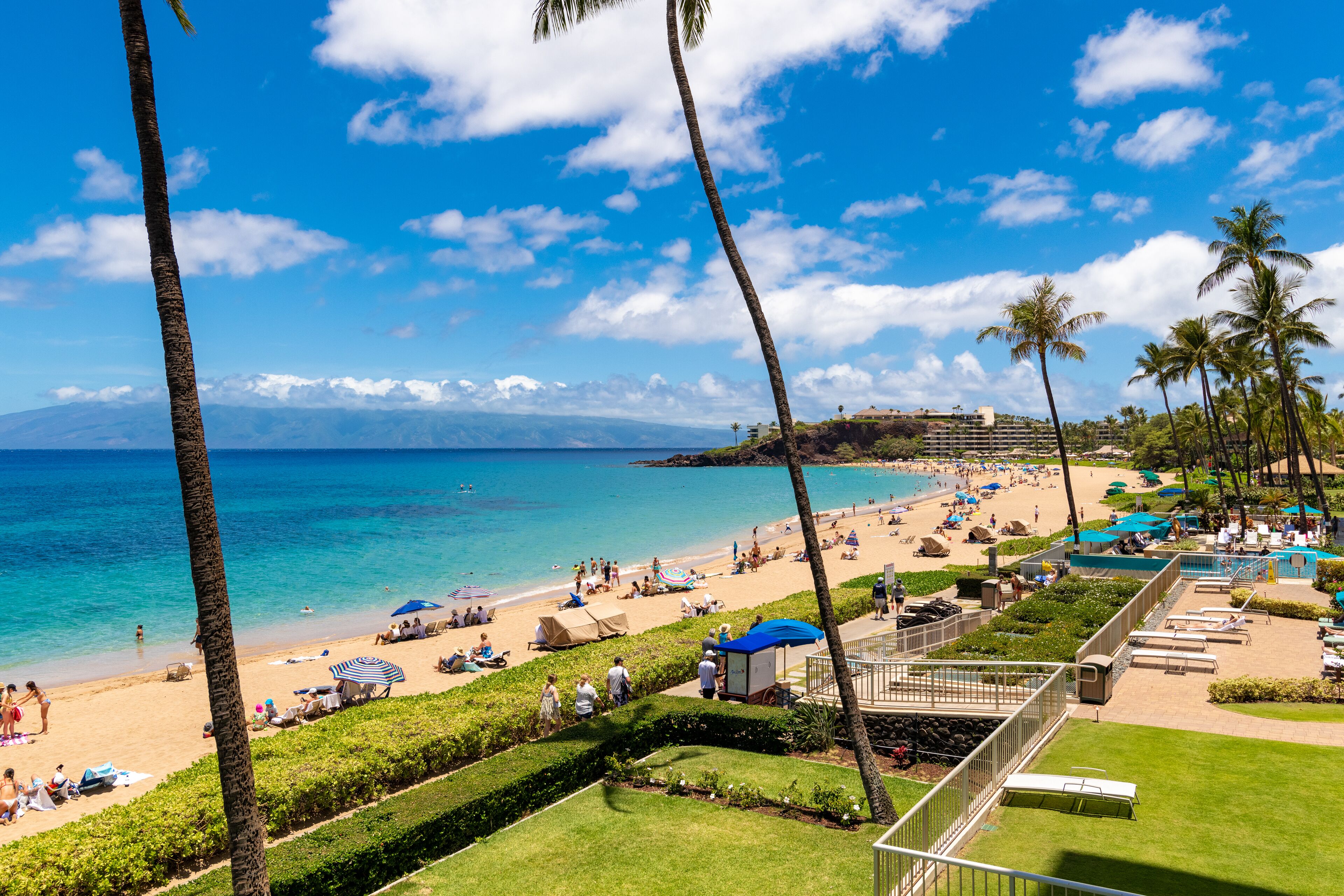 A beach resort with a pool area, lounge chairs, and a view of the ocean.