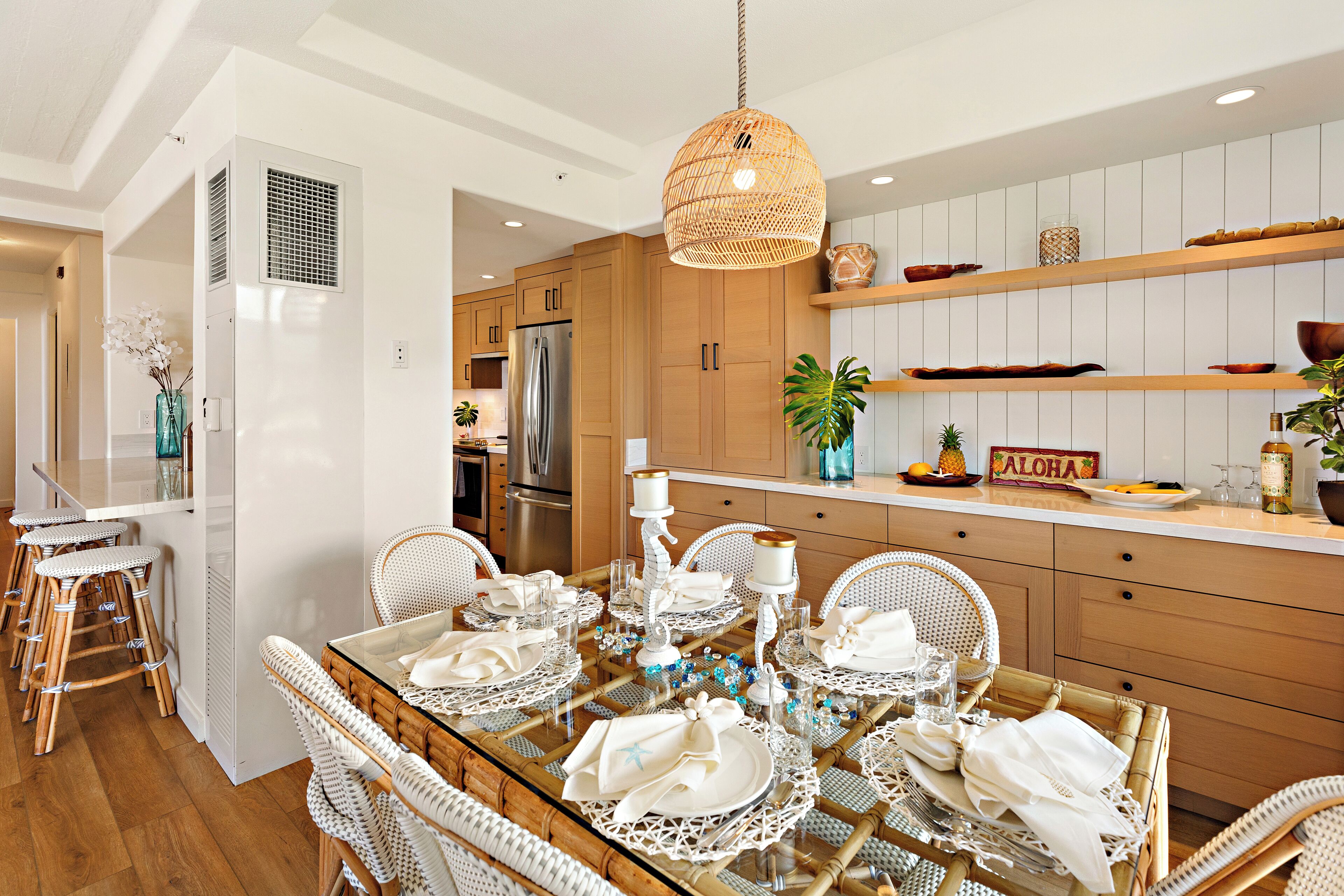 Una cocina moderna con armarios de madera, un refrigerador de acero inoxidable y un comedor listo para una comida.