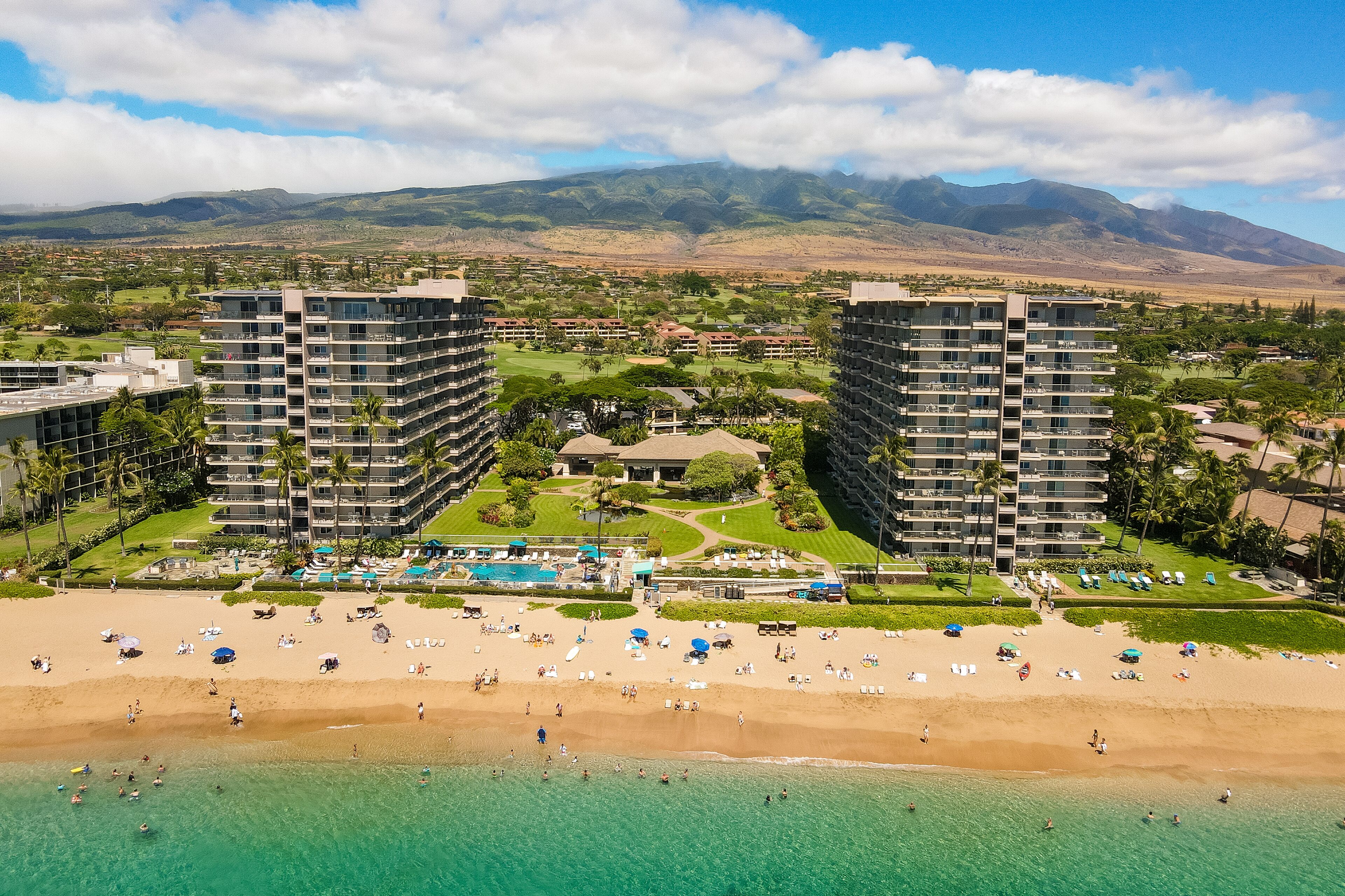 A resort with multiple high-rise buildings, a beach, and a pool area.