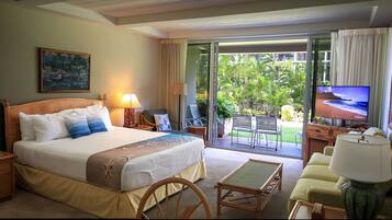 Quarto de hotel com cama grande, televisão, escrivaninha e varanda com vista para o exterior.