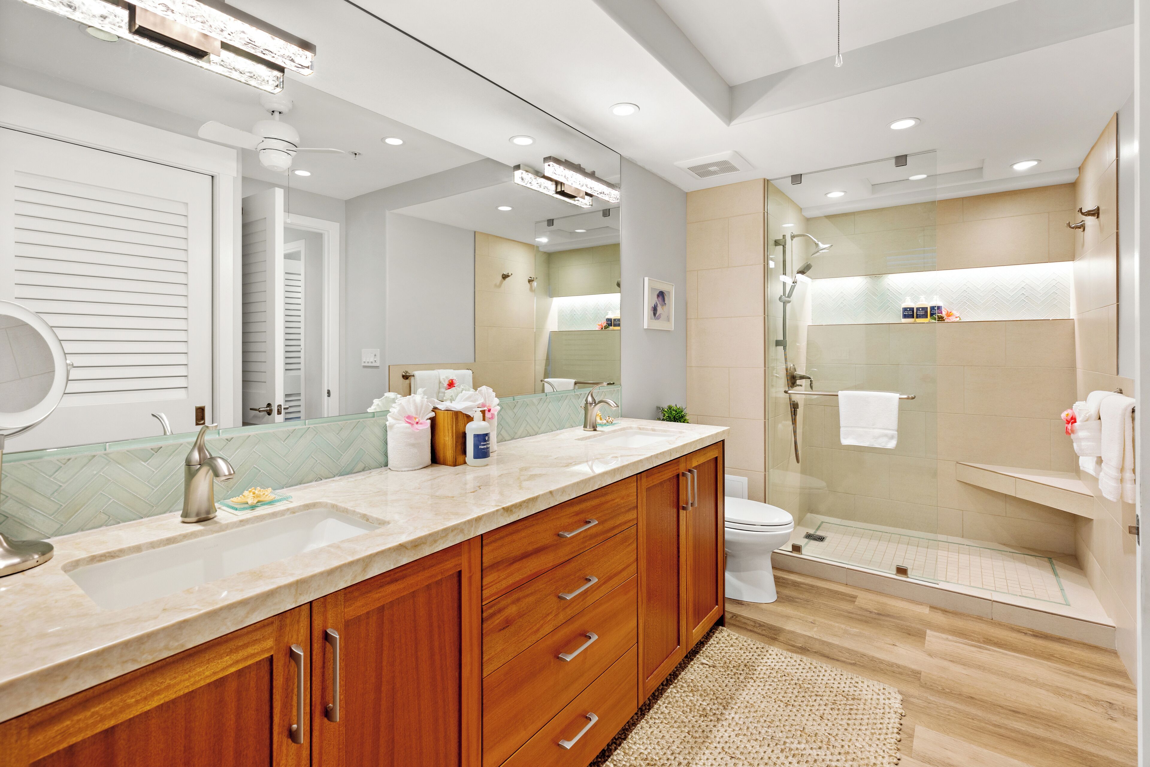 A modern bathroom with a large vanity, a glass shower enclosure, and a toilet.