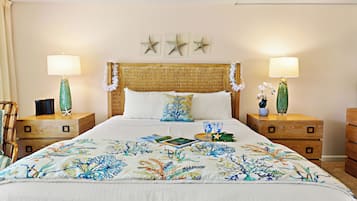 Un letto ben rifatto con una coperta a motivi floreali, due comodini con lampade e tre decorazioni a forma di stella marina.