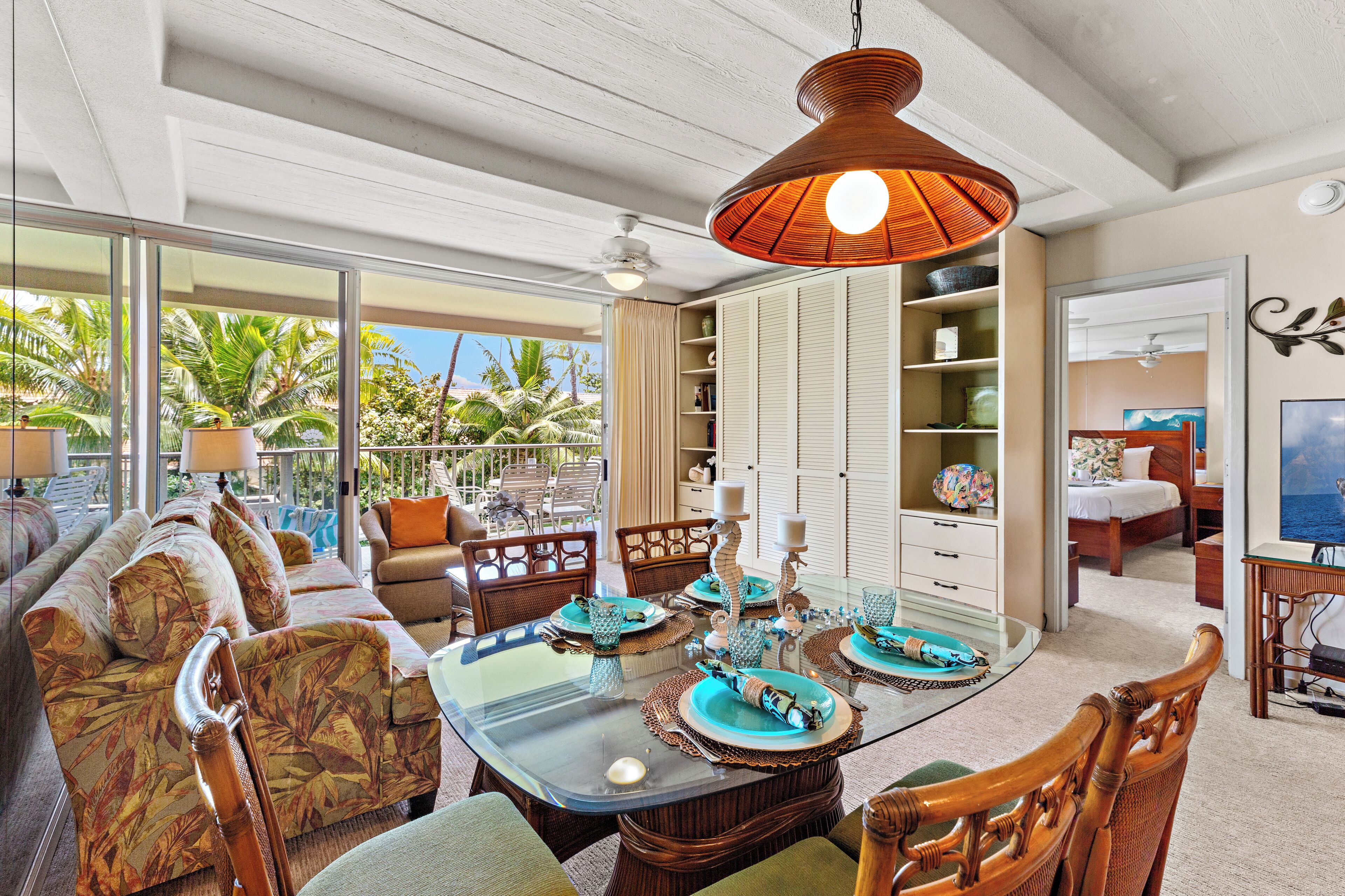A spacious living area with a large glass dining table, comfortable seating, and a view of the outdoors.