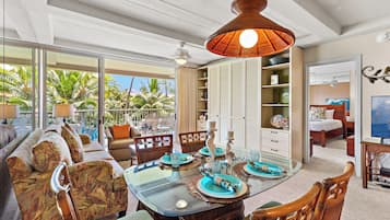 A spacious living area with a large glass dining table, comfortable seating, and a view of the outdoors.