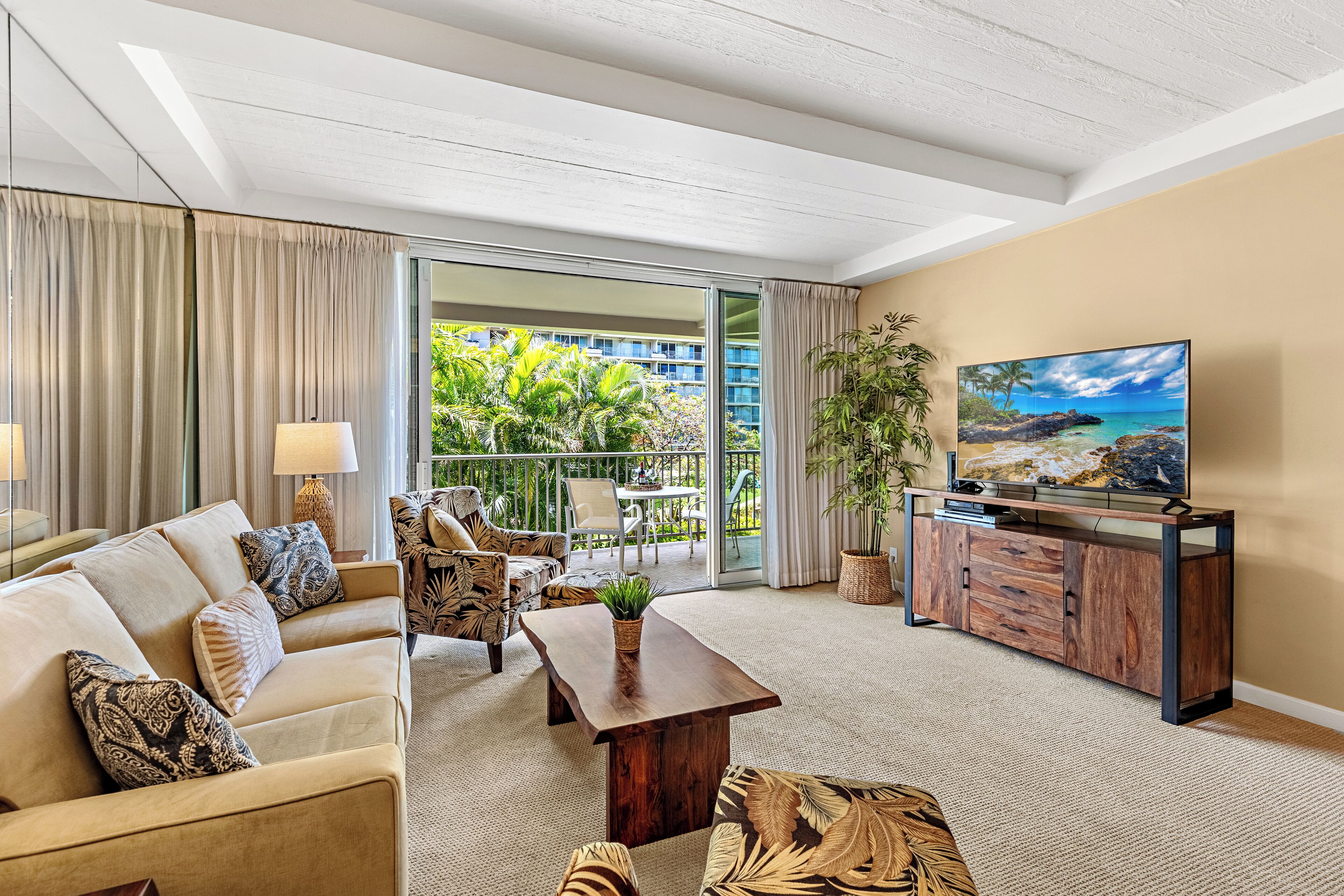 A modern living room with a sofa, armchairs, a coffee table, and a TV on a wooden cabinet.