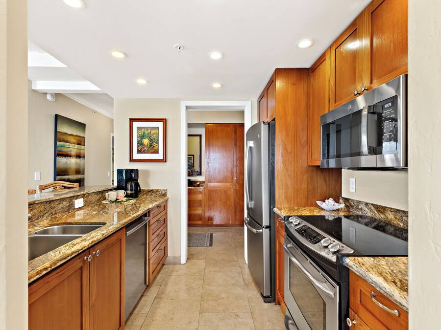 A kitchen with wooden cabinets, stainless steel appliances, granite countertops, and a framed picture on the wall.