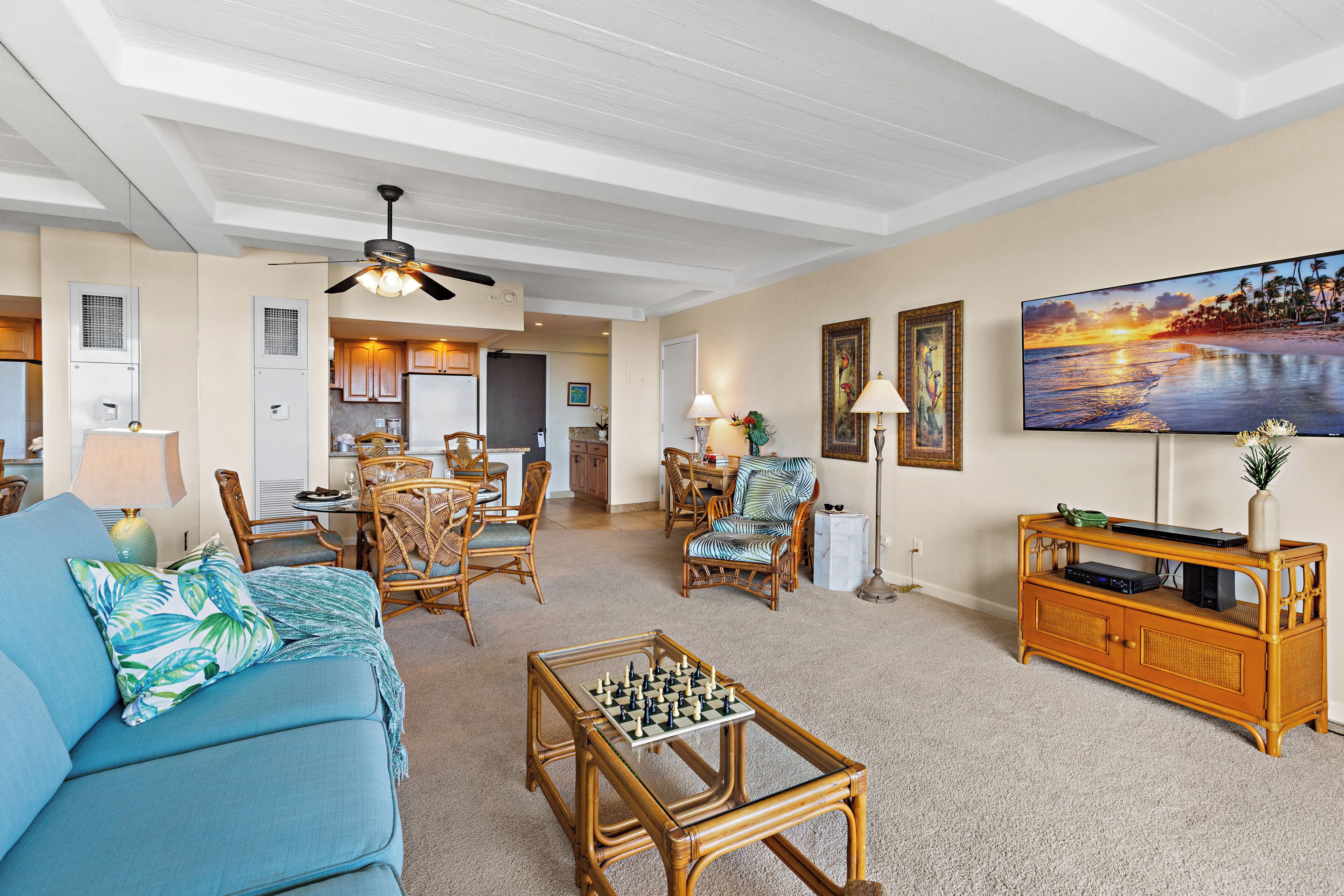 A spacious living room with a sofa, coffee table, and a television mounted on the wall.