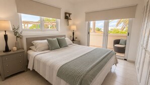 A bedroom with a bed, nightstands, a window, a balcony, and a chair. - Villa Athena GORGEOUS home with large private pool! (Noord)
