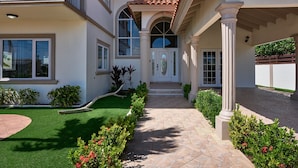 A house with a covered entrance, a tiled patio, and a well-maintained lawn. - Villa Athena GORGEOUS home with large private pool! (Noord)