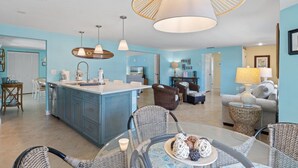 A spacious living area with a central island, wicker furniture, and a large hanging light fixture. - Da Beach House: 2 Blocks to Beach, Pool & Spa by Anna Maria Life Vacation Rentals (Holmes Beach)
