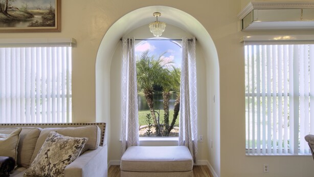 Una stanza con una panca sotto una finestra ad arco, un divano con cuscini decorati e un quadro appeso al muro.