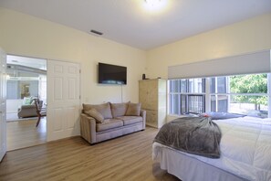 Un dormitorio con cama, sofá, televisión y ventana con vistas.
