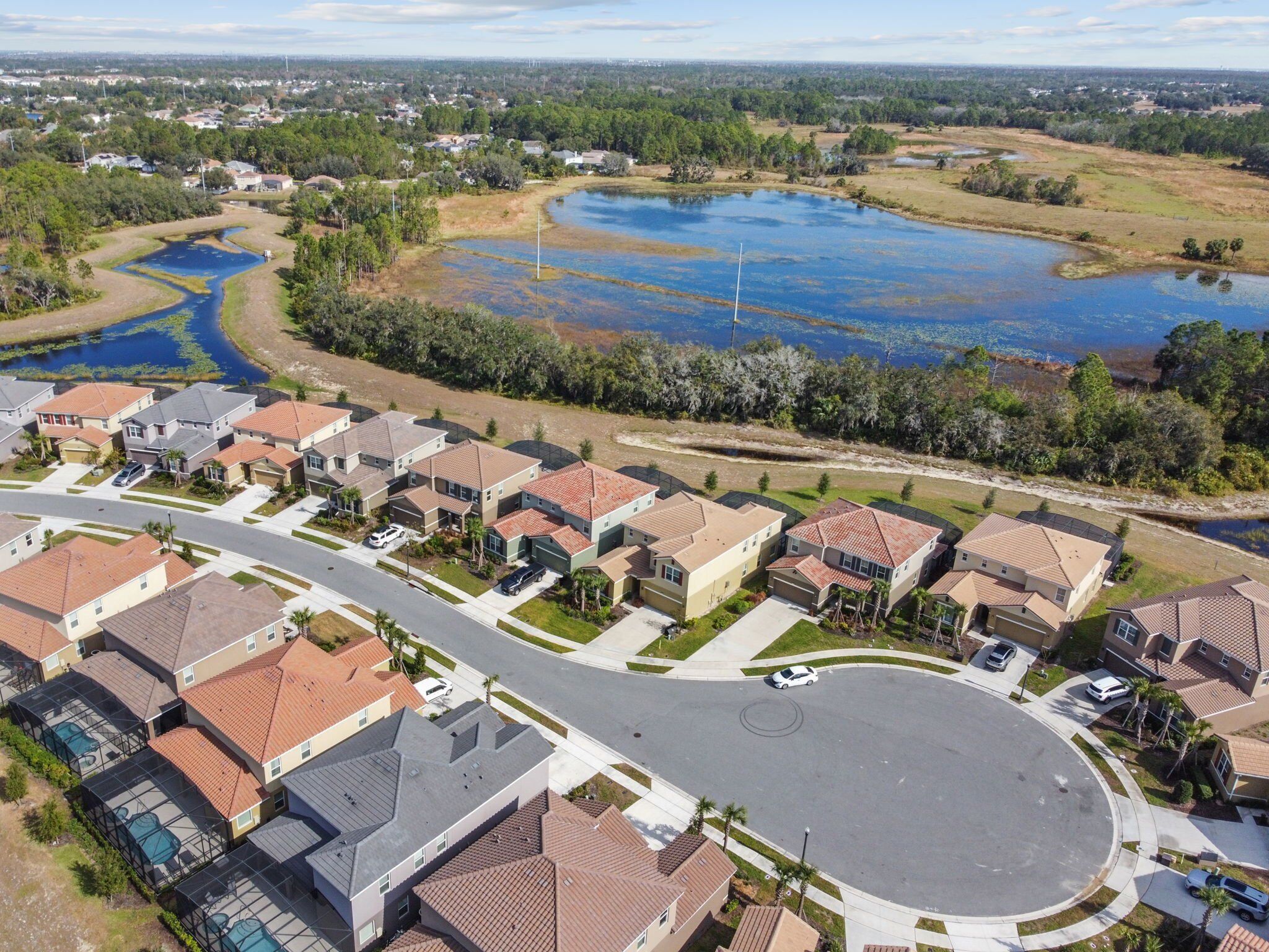 A residential area with houses, a roundabout, and a large body of water with vegetation.