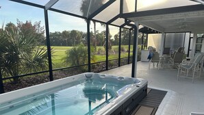 Uma banheira de hidromassagem com vista para um jardim e um espaço de pátio com cadeiras e mesas.