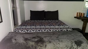 Un lit avec une couvre-lit à motifs et deux oreillers noirs.
