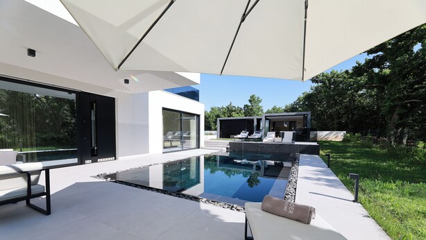 A modern outdoor pool area with a glass enclosure, a lounge chair, and a covered seating area. - Luxury Villa Cloer, Jadranovo/Crikvenica (Jadranovo)
