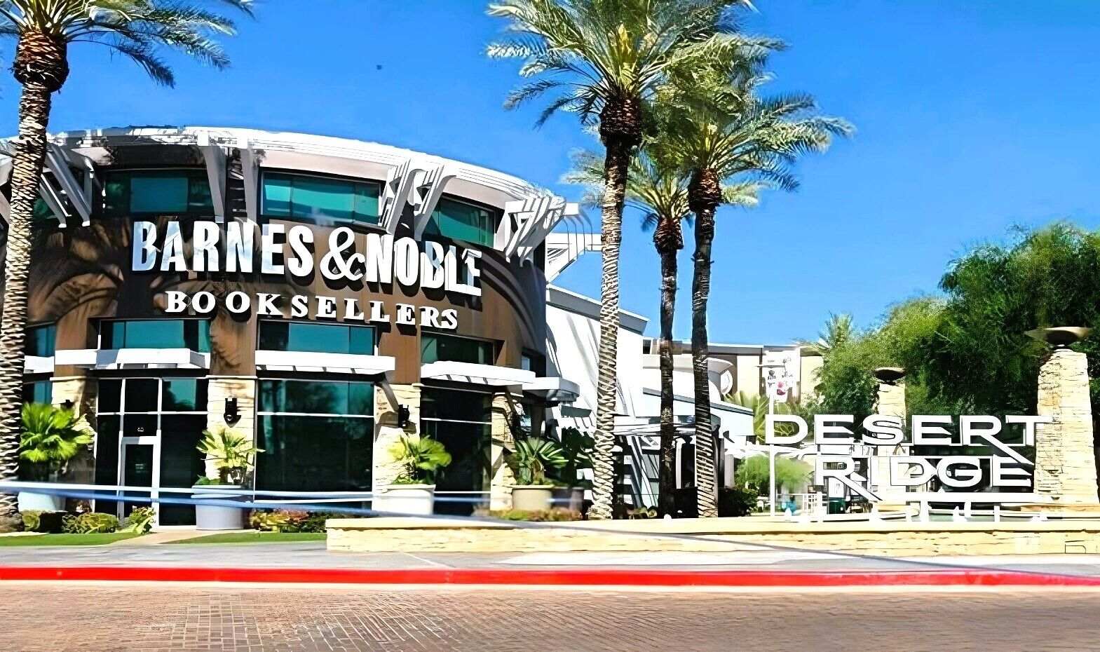 Edifici de Barnes & Noble Booksellers de disseny modern, palmeres i un cel blau clar.