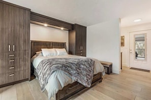A bedroom with a bed, wooden wardrobe, and a bench.