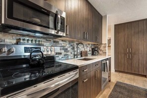 Una cocina moderna con electrodomésticos de acero inoxidable, gabinetes de madera y salpicadero de azulejos.