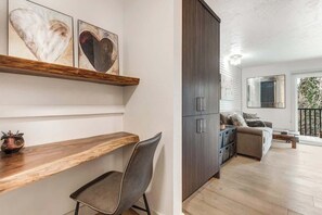 Una sala moderna con un banco de madera, un sofá, un armario y arte abstracto en la pared.
