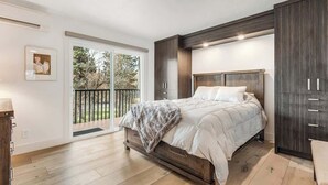 Un dormitorio con cama, armario, puerta que da a un balcón y un cuadro en la pared.