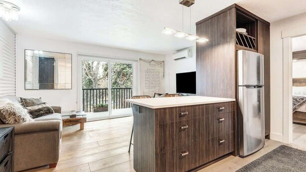 Una cocina moderna con una isla central, armarios de madera y un refrigerador de acero inoxidable.