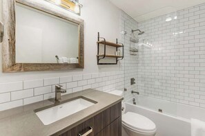 Un baño con lavamanos, espejo, inodoro y ducha.