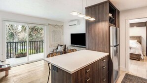 Una cocina moderna con una isla grande, un refrigerador integrado y un comedor con sillas.