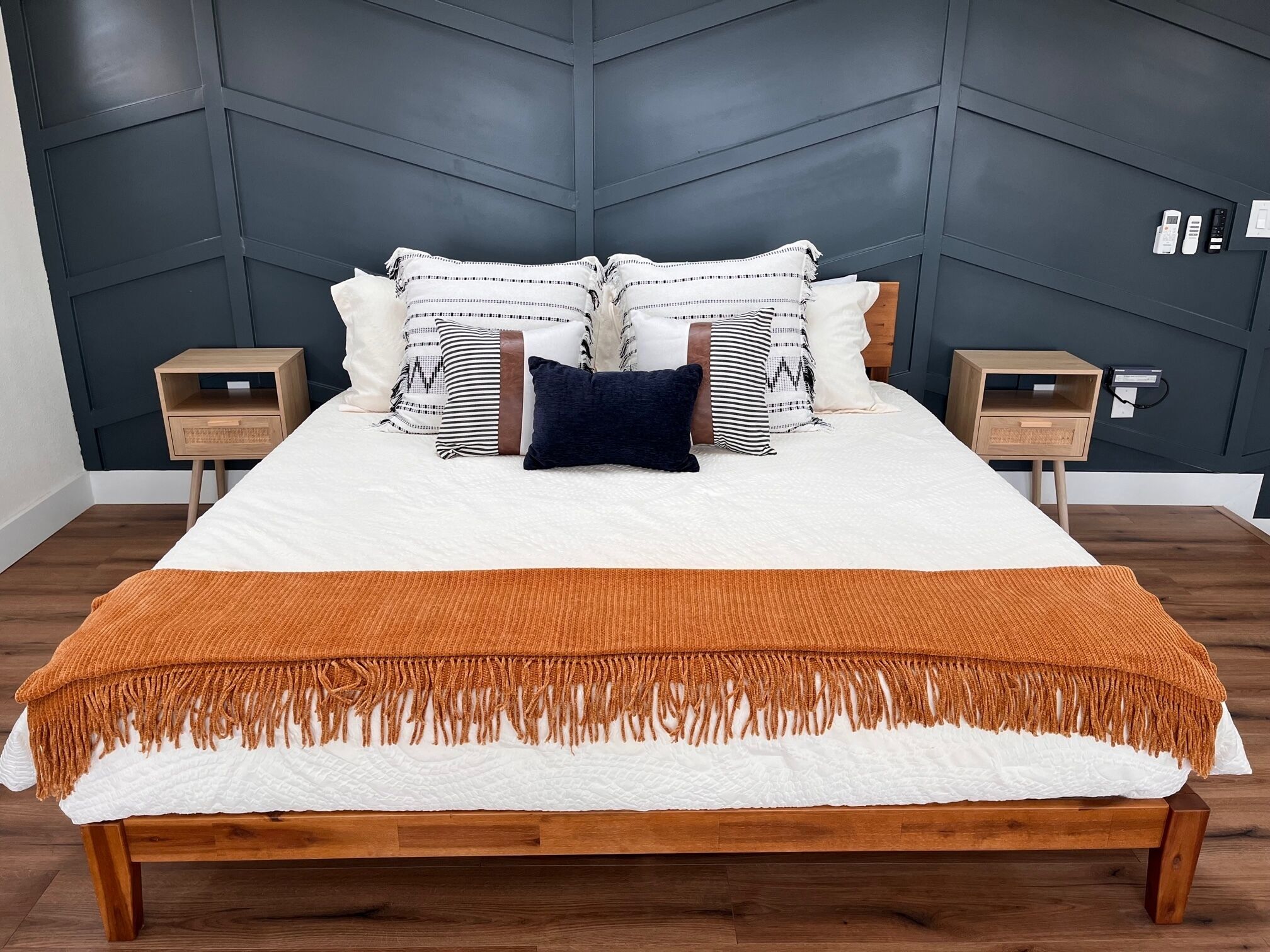 A bedroom with a bed, two nightstands, a headboard, and a bedside table.