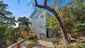 A modern house with a wooden deck and a gravel path leading to the entrance. - Travis Treehouse, Private Couples Getaway  (Austin)