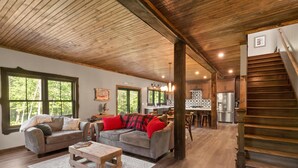A spacious living room with a wooden ceiling, a dining area, and a kitchen.