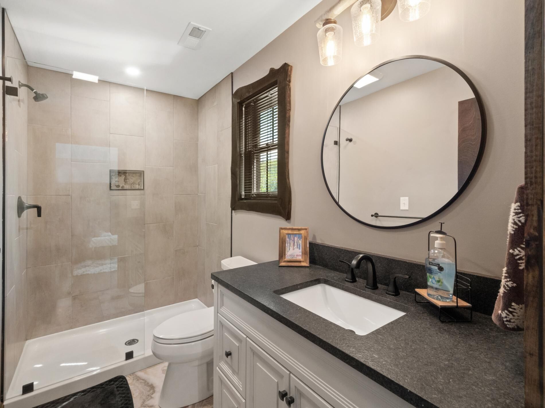 A modern bathroom with a shower, toilet, sink, and vanity.