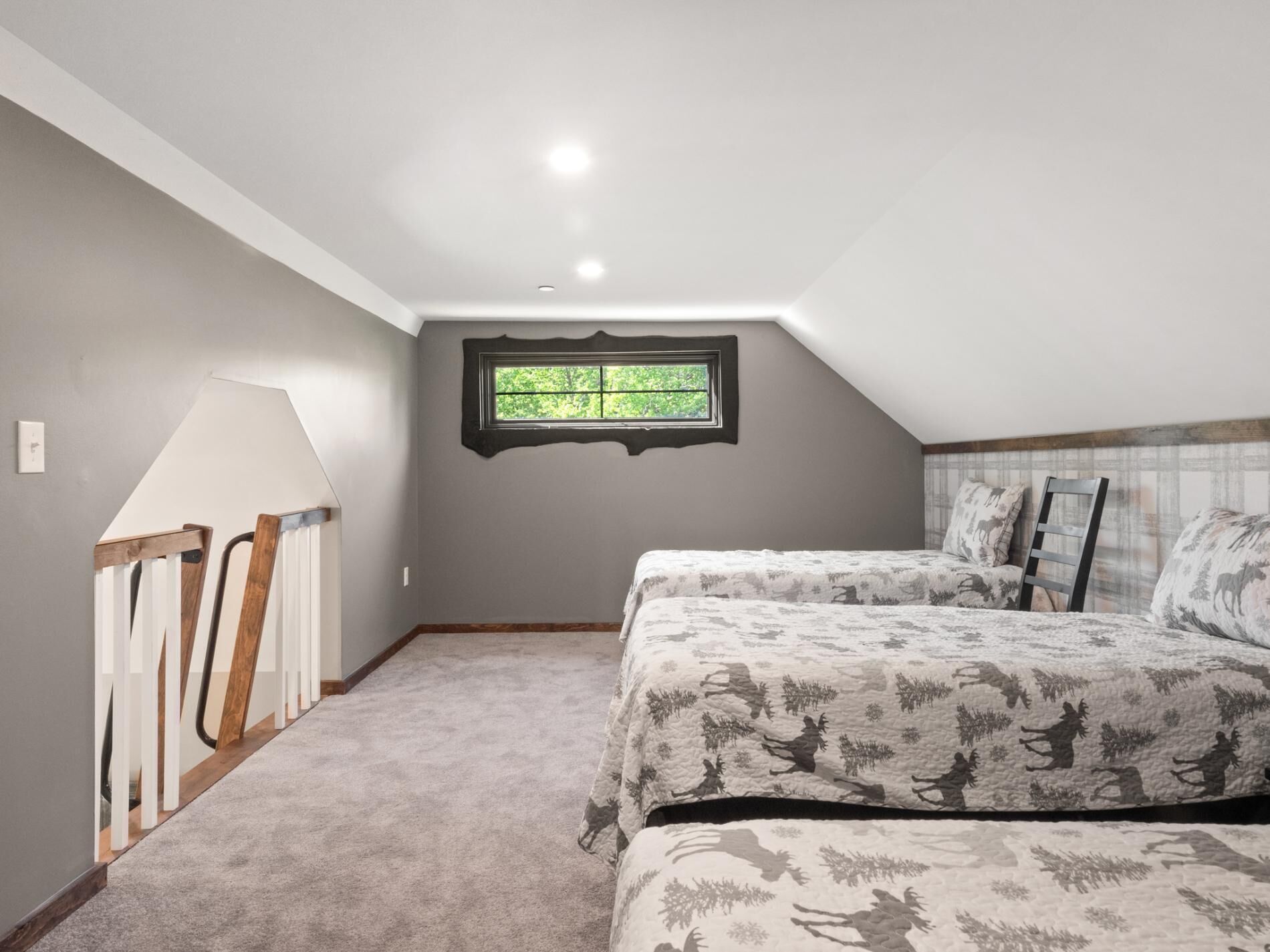 A bedroom with two beds, a window, and a sloped ceiling.