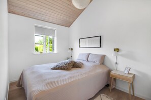 Une chambre à coucher avec un lit, une fenêtre, une table de chevet et une lampe.