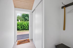 Ein Zimmer mit Holzboden, einer Schiebetür zu einem Außenbereich und einer Sitzbank.