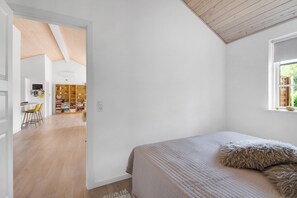 Ein Schlafzimmer mit einem Bett, einem Fenster und einer Holzbalkendecke.