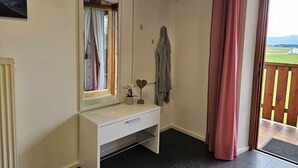 A room with a white console desk, a mirror, a towel rack, and a view of a green landscape through a door. - Steinplatte vacation apartment, 3-star with 45 sqm, home, balcony (Gstadt am Chiemsee)
