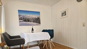 A dining area with a table set for two, a sofa, and a chair. - Steinplatte vacation apartment, 3-star with 45 sqm, home, balcony (Gstadt am Chiemsee)