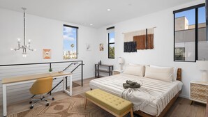 A modern bedroom with a large bed, a desk, and a bench.